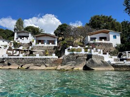 Una propiedad costera con edificios blancos, agua turquesa cristalina y terreno rocoso.