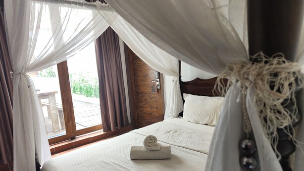 A bedroom with a bed, curtains, and a wooden headboard. - Armenian Suite (George Town)