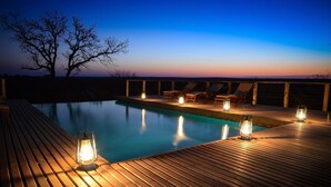 Un pontile in legno con piscina, poltrona da relax e lanterne.