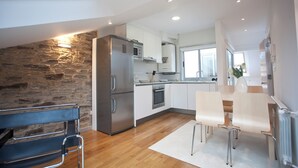 Una cocina moderna con pared de piedra, electrodomésticos de acero inoxidable y un comedor con banco y sillas.