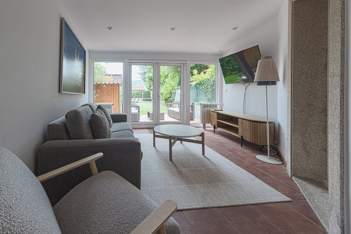 A modern living room with a grey sofa, a round coffee table, and a TV on a stand.