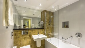 A modern bathroom with a glass-enclosed shower, a white sink, and a bathtub.