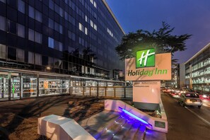 Señal de Holiday Inn con un edificio moderno al fondo.