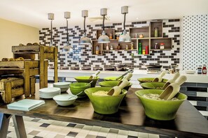 A modern kitchen with a checkered backsplash, wooden furniture, and green bowls with wooden utensils. - Holiday Inn London - Watford Junction by IHG (Watford)