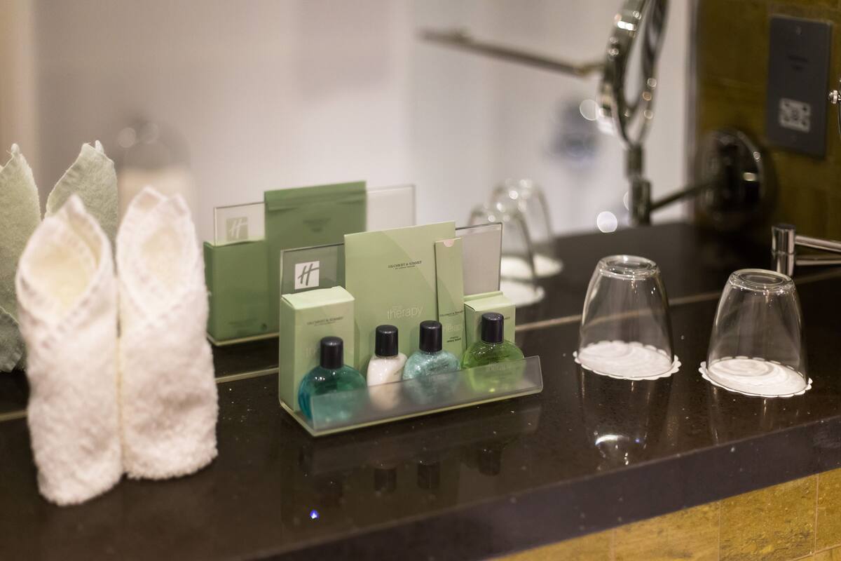 A hotel reception area with a counter displaying toiletries, a mirror, and a pair of slippers.