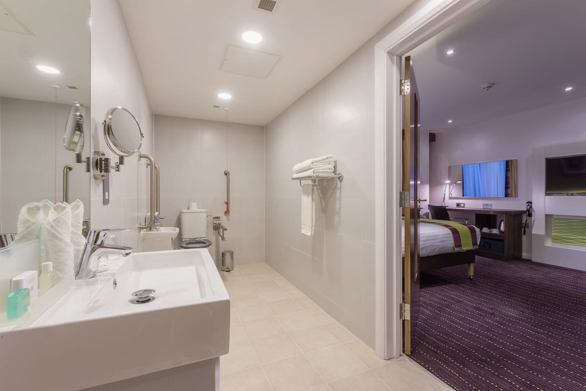 A modern hotel bathroom with a large sink, mirror, and towel rack.