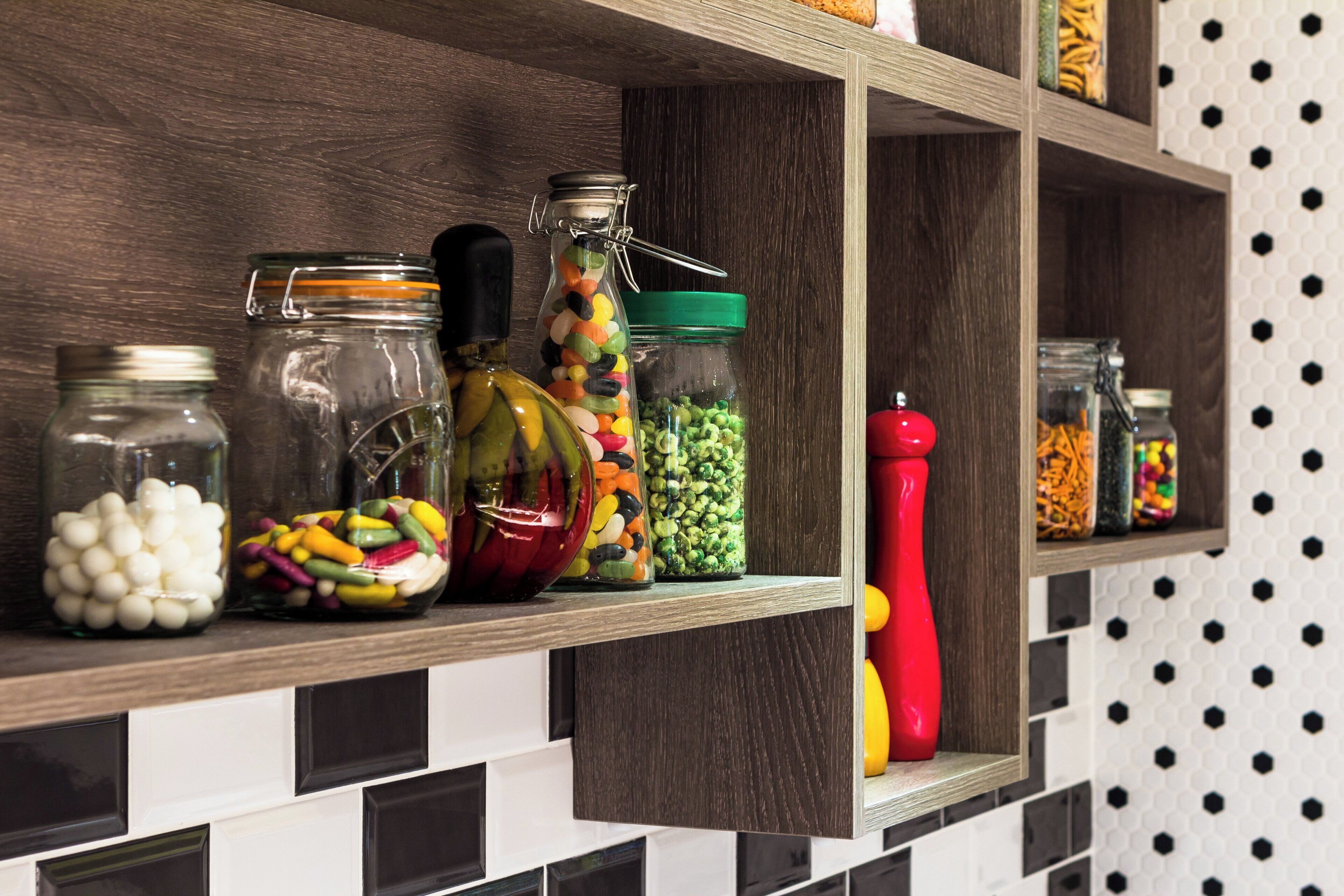 A kitchen shelf with various glass jars containing different food items.