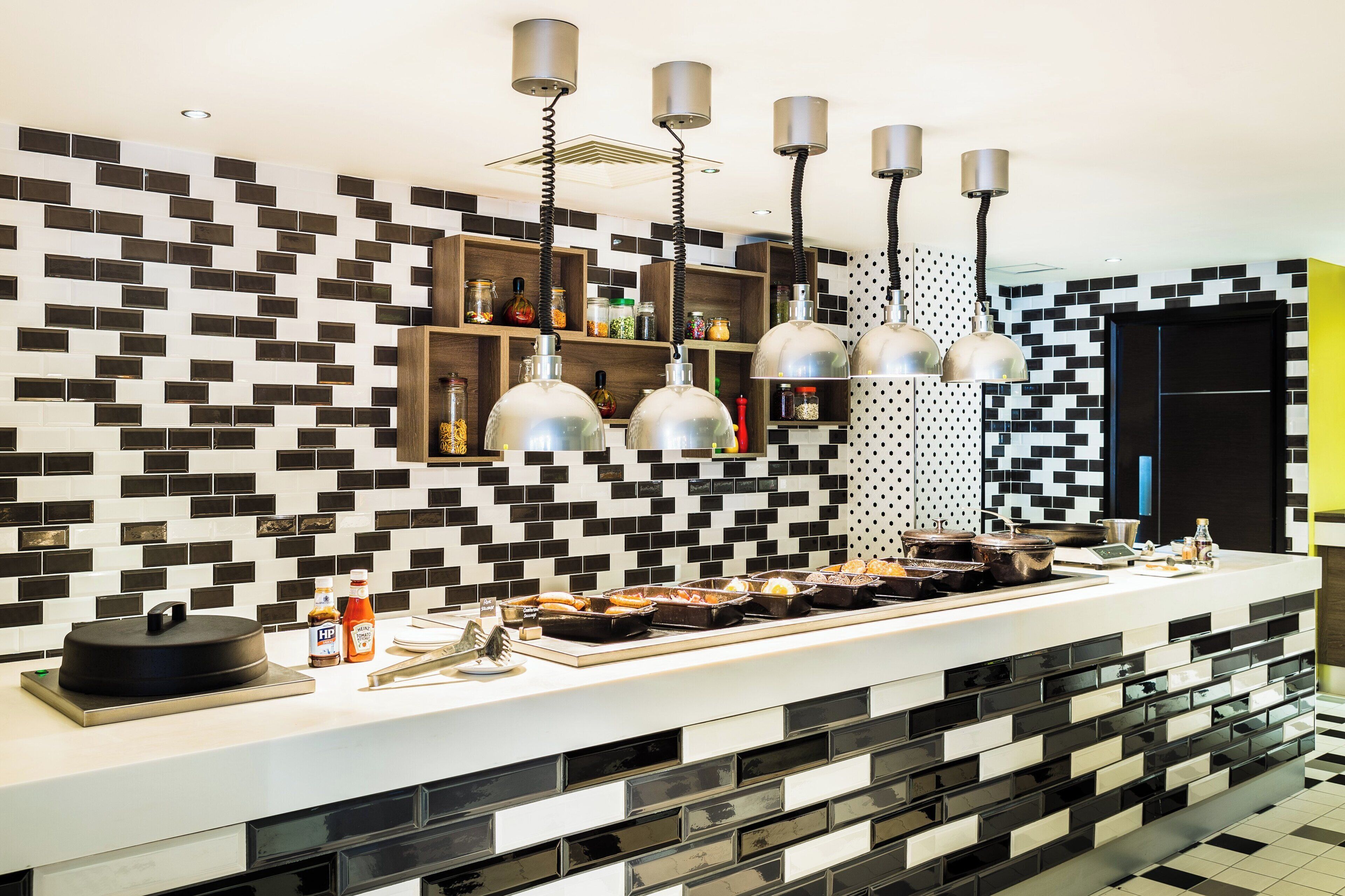 Una cocina moderna con un salpicadero de azulejos blanco y negro, luces colgantes y un aparador.