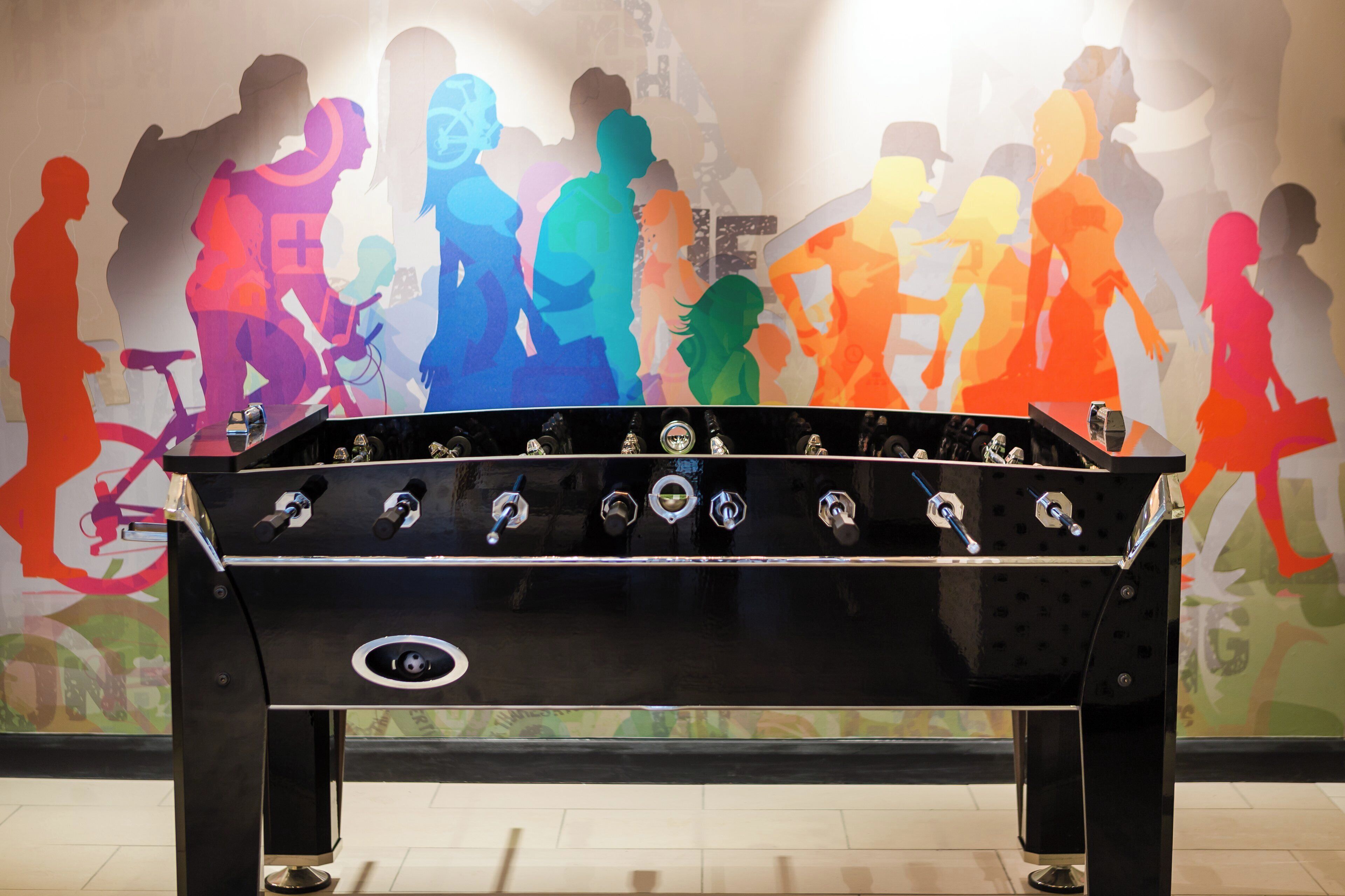 A foosball table in a room with a colorful mural on the wall.