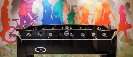 A foosball table in a room with a colorful mural on the wall.