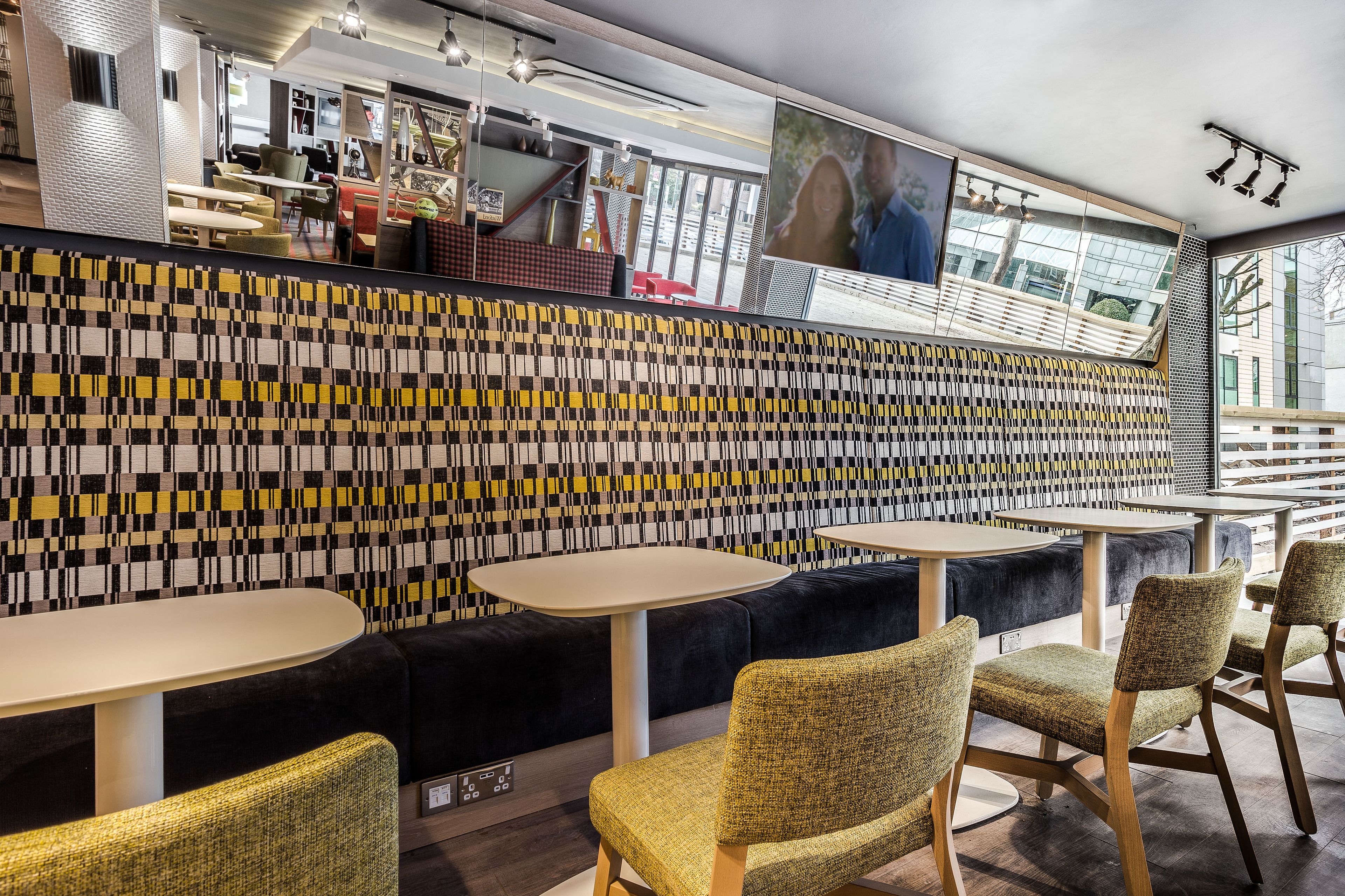 Un intérieur moderne avec un mur décoré de motifs, des coins salon et une grande fenêtre.