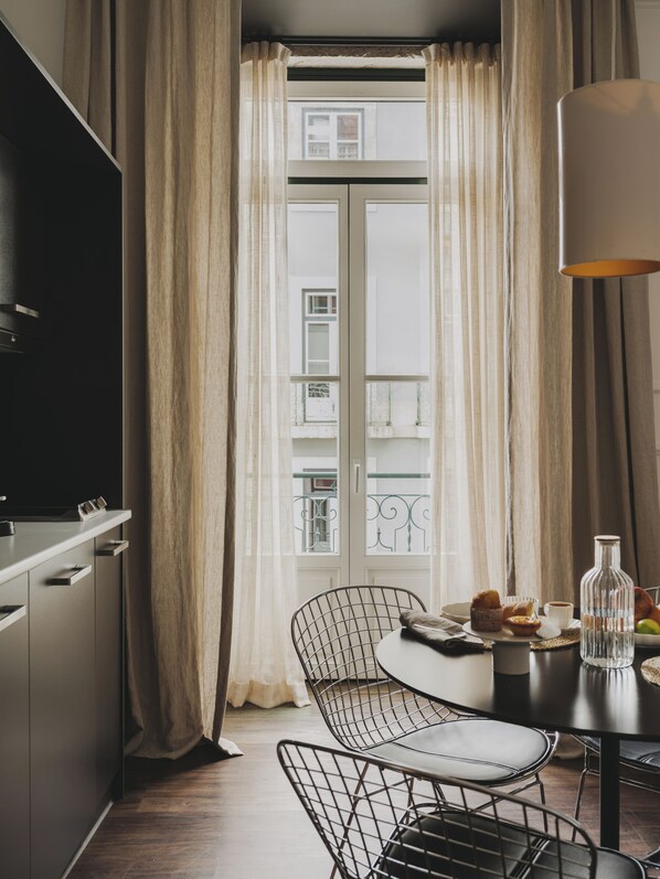 Cocina moderna con comedor, con un amplio ventanal con cortinas, una mesa de comedor y sillas, y una encimera de cocina.