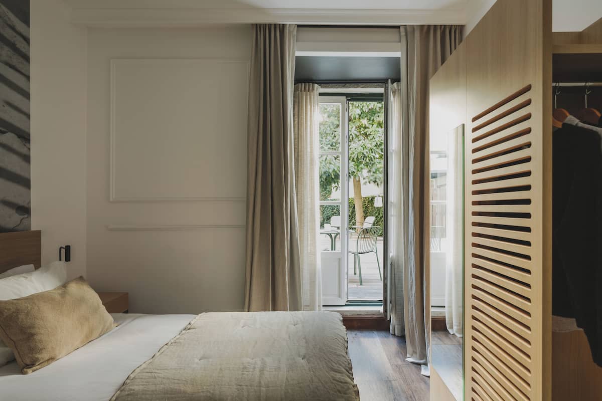 Een slaapkamer met een bed, een houten garderobe en uitzicht op het omliggende landschap.