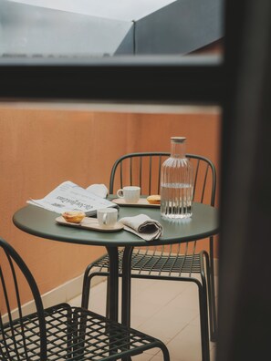 Uma pequena mesa redonda com um menu, uma garrafa de vidro, um muffin e uma chávena.