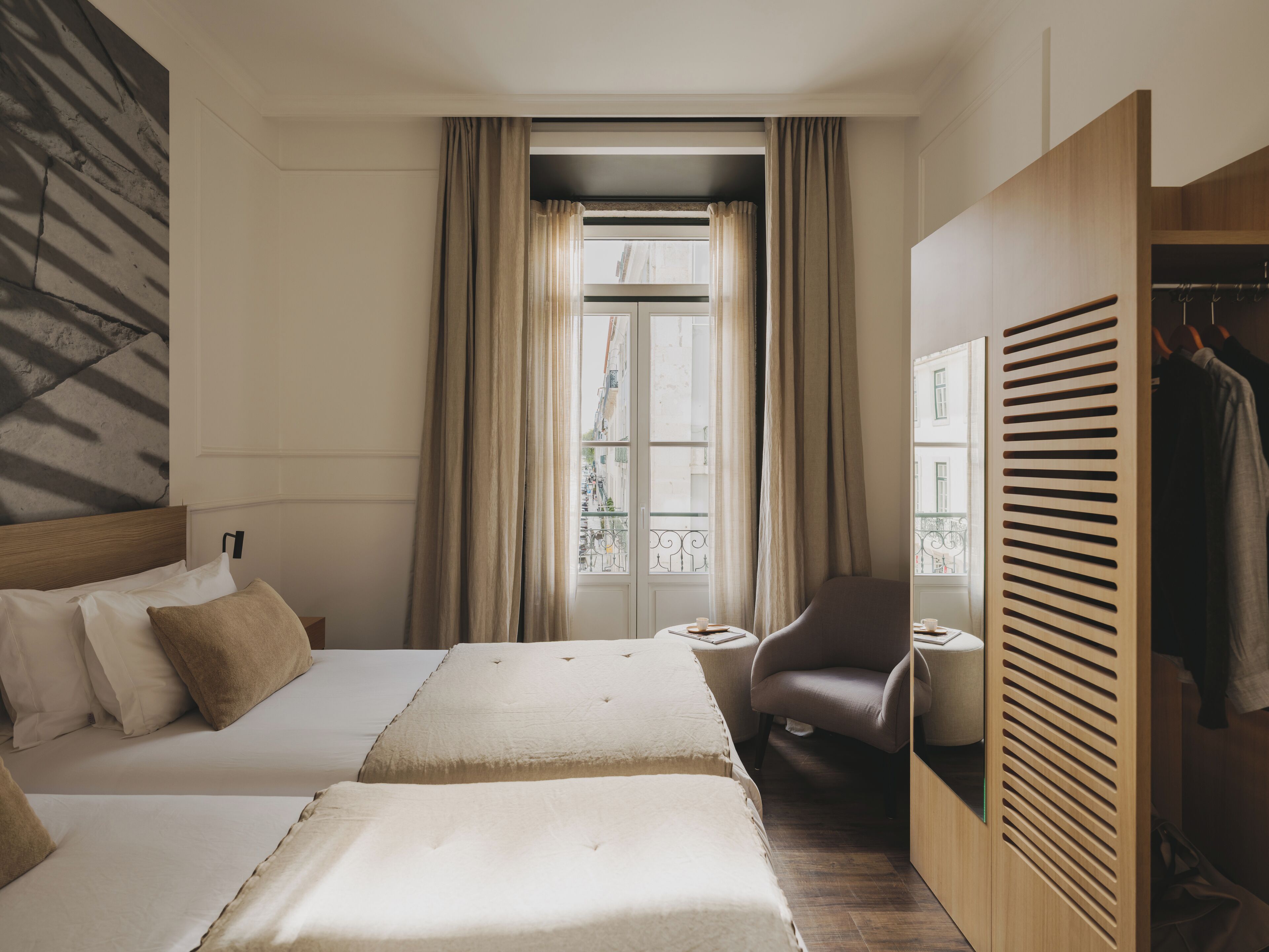 Ein Hotelzimmer mit zwei Betten, einem Sessel, einem kleinen Tisch und einem Kleiderschrank.