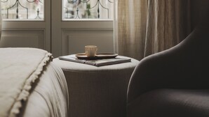 Una habitación con una cama, una ventana con cortinas y vistas a edificios.