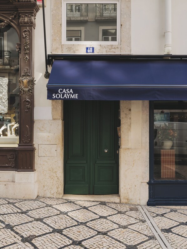 Un edificio con puerta verde y toldo azul que muestra el nombre 'Casa Solayme'.
