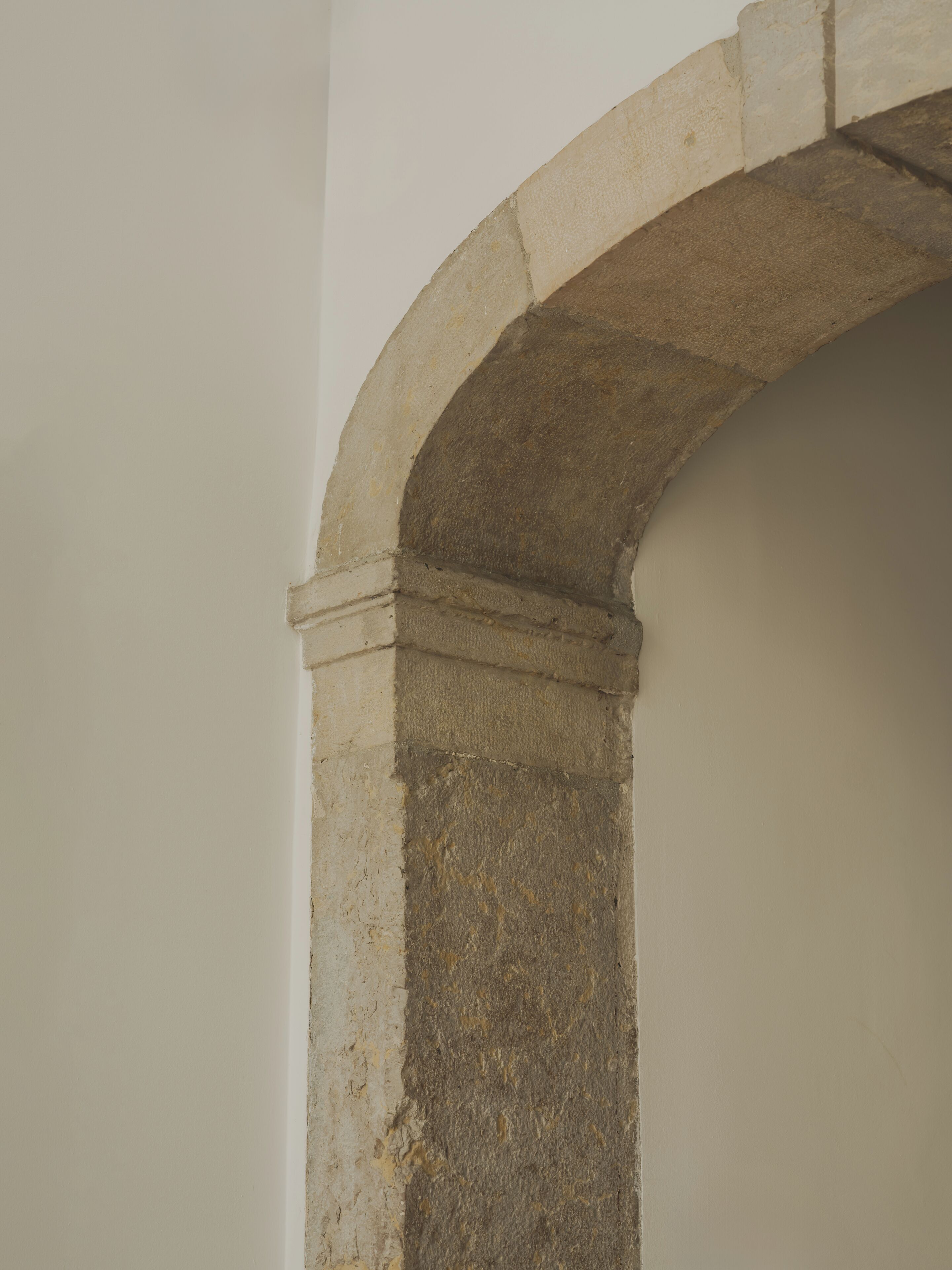 A stone archway with a rough texture, likely part of a building's architecture.