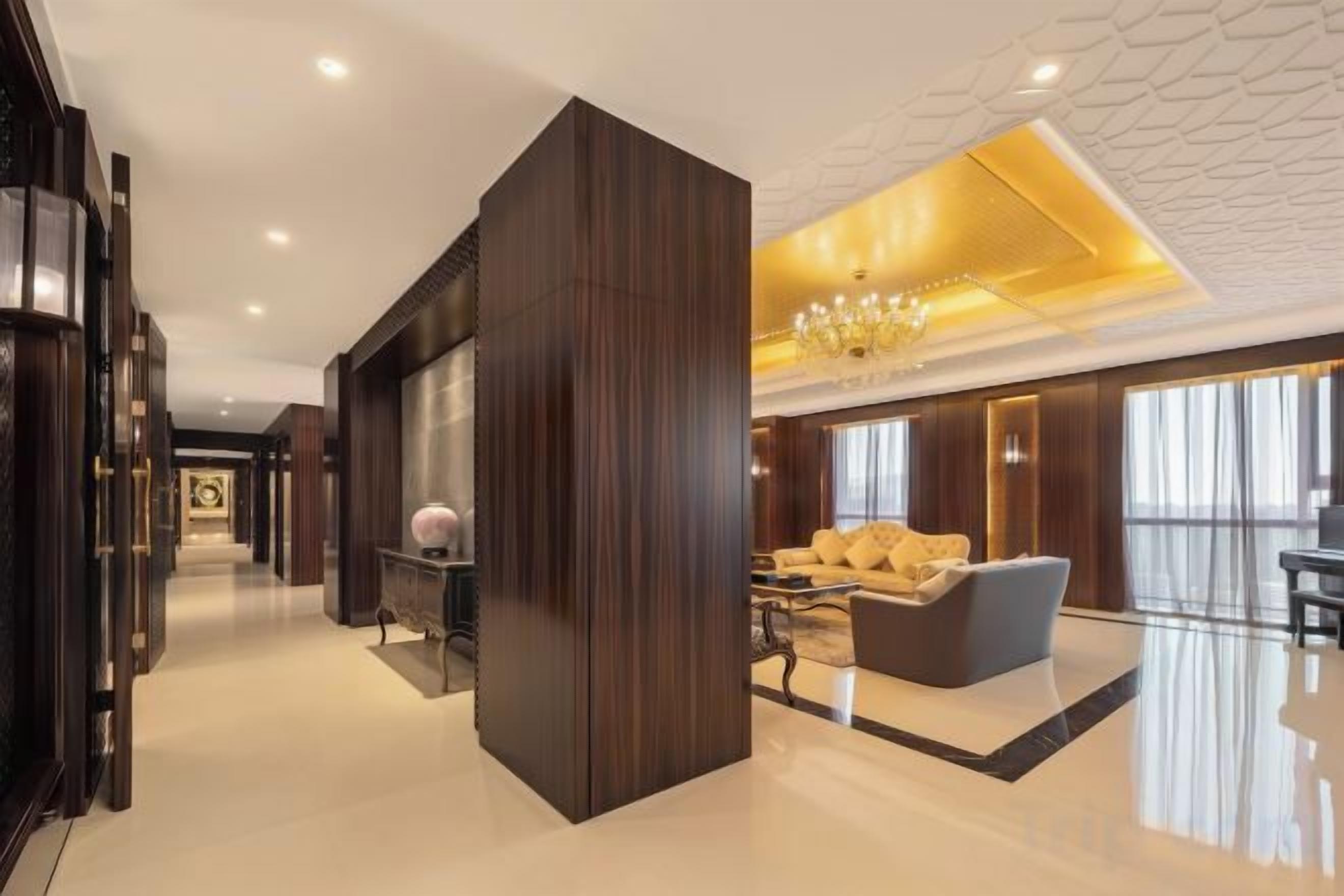A spacious lobby with a high ceiling, a grand chandelier, and a seating area with a sofa and armchairs.