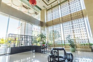 A spacious lobby with a seating area, large windows, and a decorative wall. - Petroleum Hotel (Yulin)