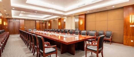 Une salle de conférence dotée d’une longue table et de chaises, équipée de microphones et recouverte d’un tapis.