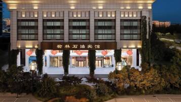 A hotel with a modern facade, large windows, and a sign in a foreign language.