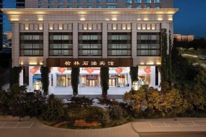 Un hotel con fachada moderna, varios pisos y una entrada destacada con señalización.