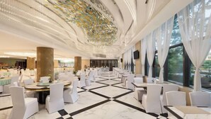 A spacious hotel lobby with a checkered floor, white chairs, and tables arranged for dining. - Petroleum Hotel (Yulin)