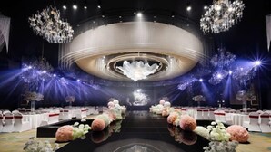 A grand hall with a circular stage, chandeliers, and floral arrangements. - Petroleum Hotel (Yulin)