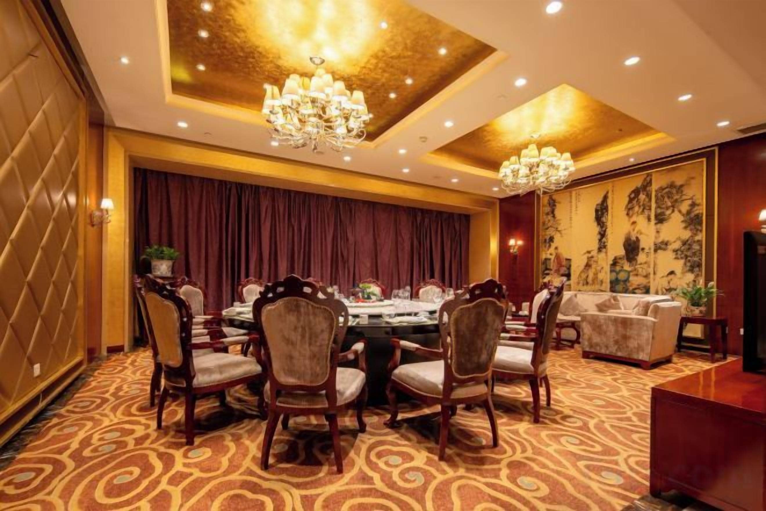A formal dining room with a round table, chairs, and a chandelier.