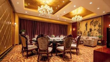 A formal dining room with a round table, chairs, and a chandelier.