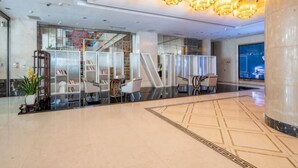 A hotel lobby with a reception desk, seating area, and a large window. - Petroleum Hotel (Yulin)