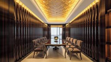 A conference room with a long table and chairs, wooden paneling on the walls, and a patterned ceiling.