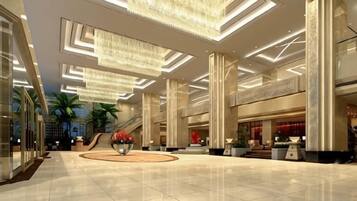 A spacious lobby with a high ceiling, large chandeliers, and a central circular floral arrangement.