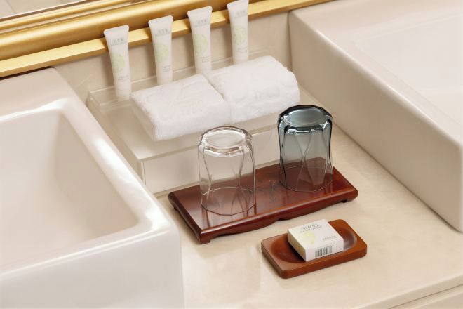 A bathroom with a bathtub, a towel rack with folded towels, and two glass containers on a wooden tray.