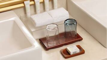A bathroom with a bathtub, a towel rack with folded towels, and two glass containers on a wooden tray.