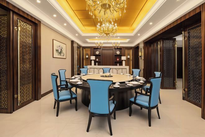 A conference room with a round table, blue chairs, and a chandelier.