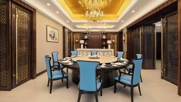A conference room with a round table, blue chairs, and a chandelier.
