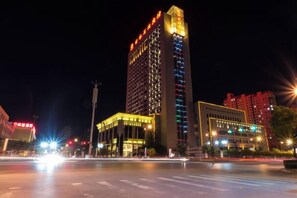 Un immeuble de grande hauteur, doté d’une enseigne lumineuse et d’une façade bien éclairée la nuit.