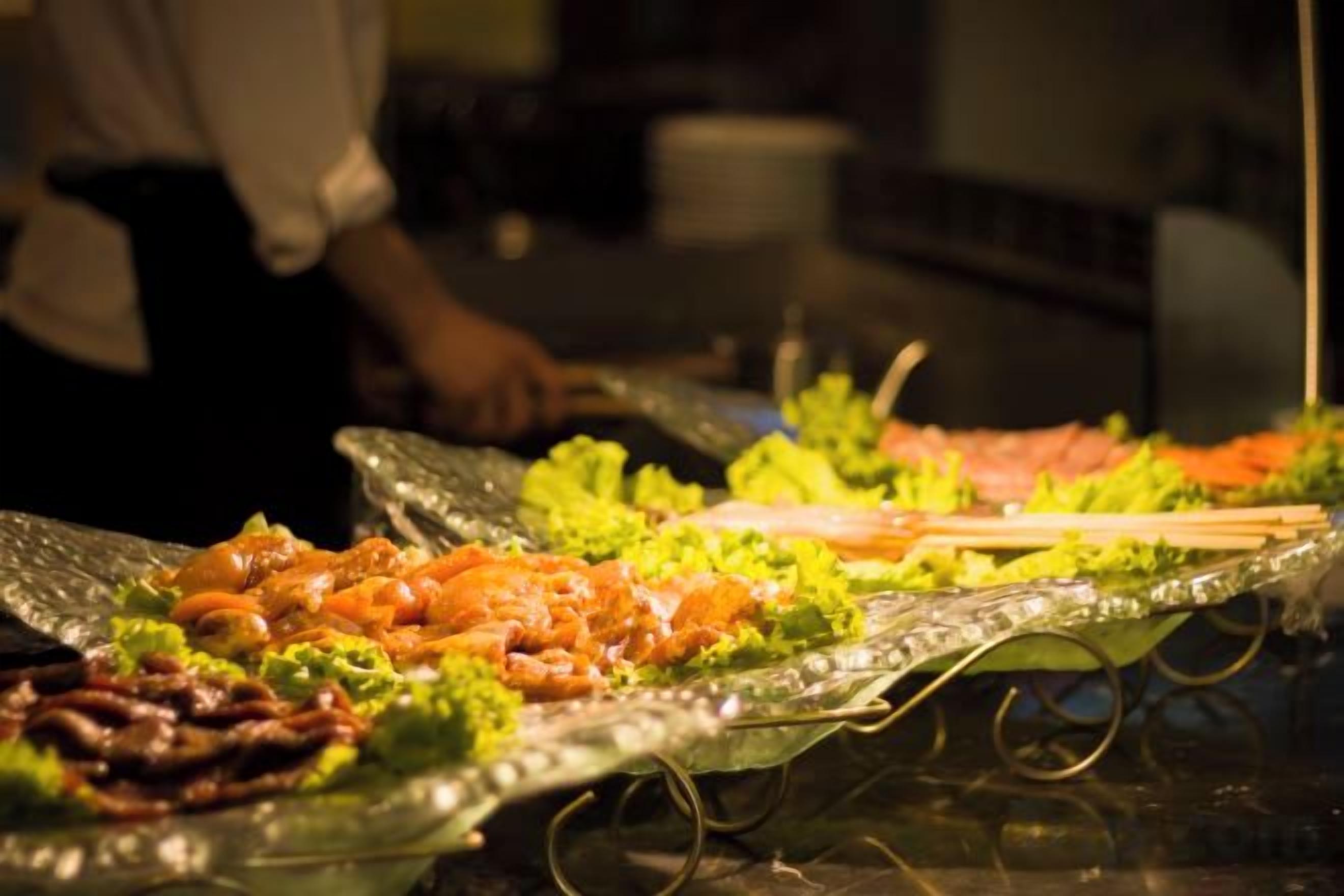 A buffet with various dishes, including seafood and vegetables, on a glass table.