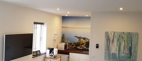 A compact living space with a kitchenette, a dining area, and a seating area with a view of the sea.