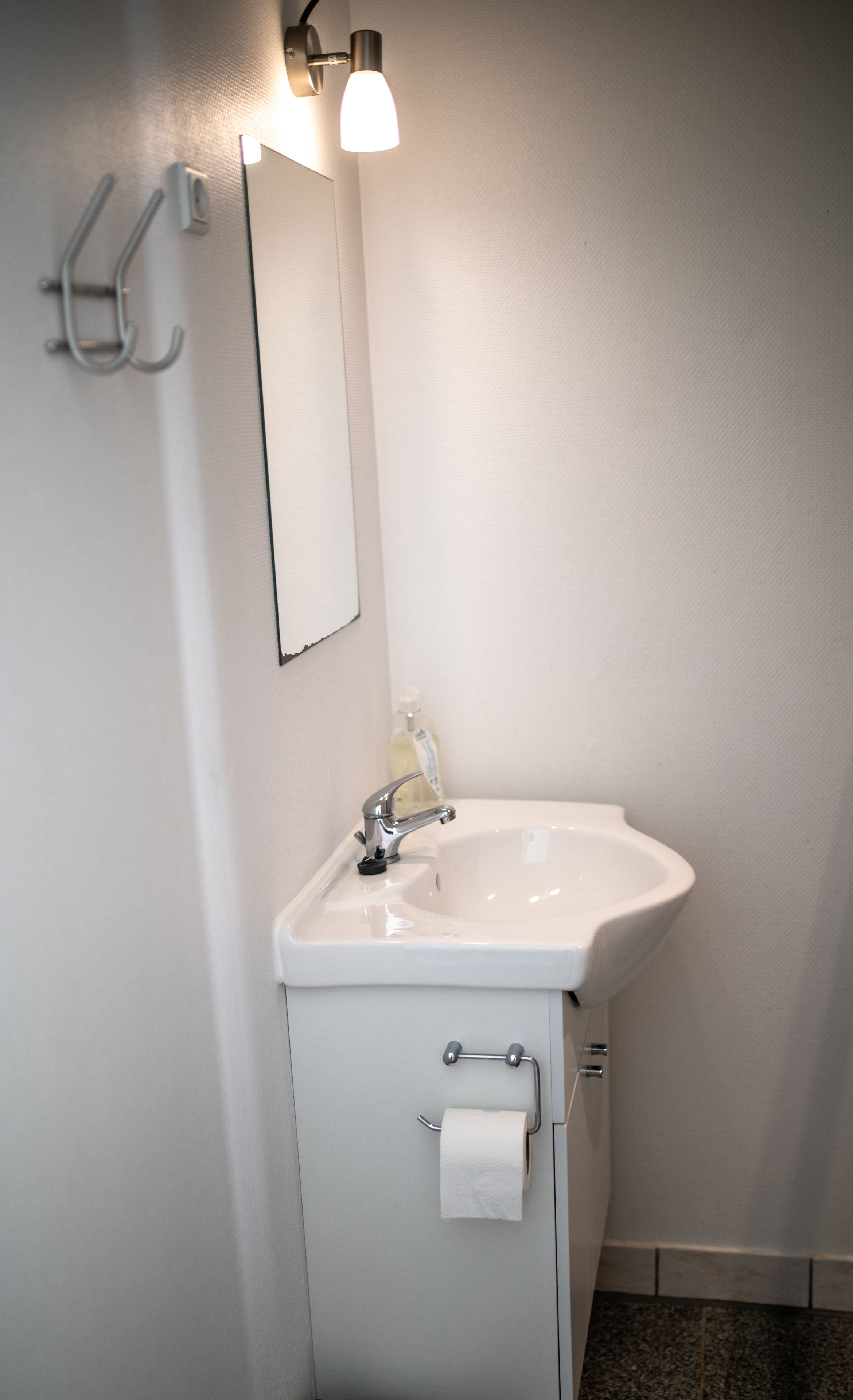 A bathroom with a white sink, a mirror, and a towel rack.