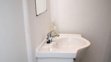 A bathroom with a white sink, a mirror, and a towel rack.