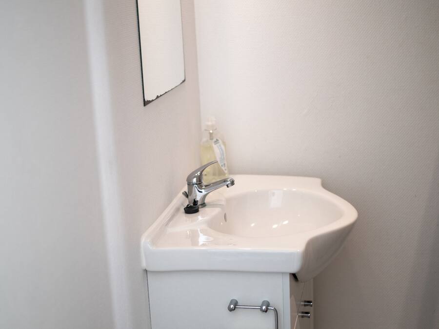 A bathroom with a white sink, a mirror, and a towel rack.
