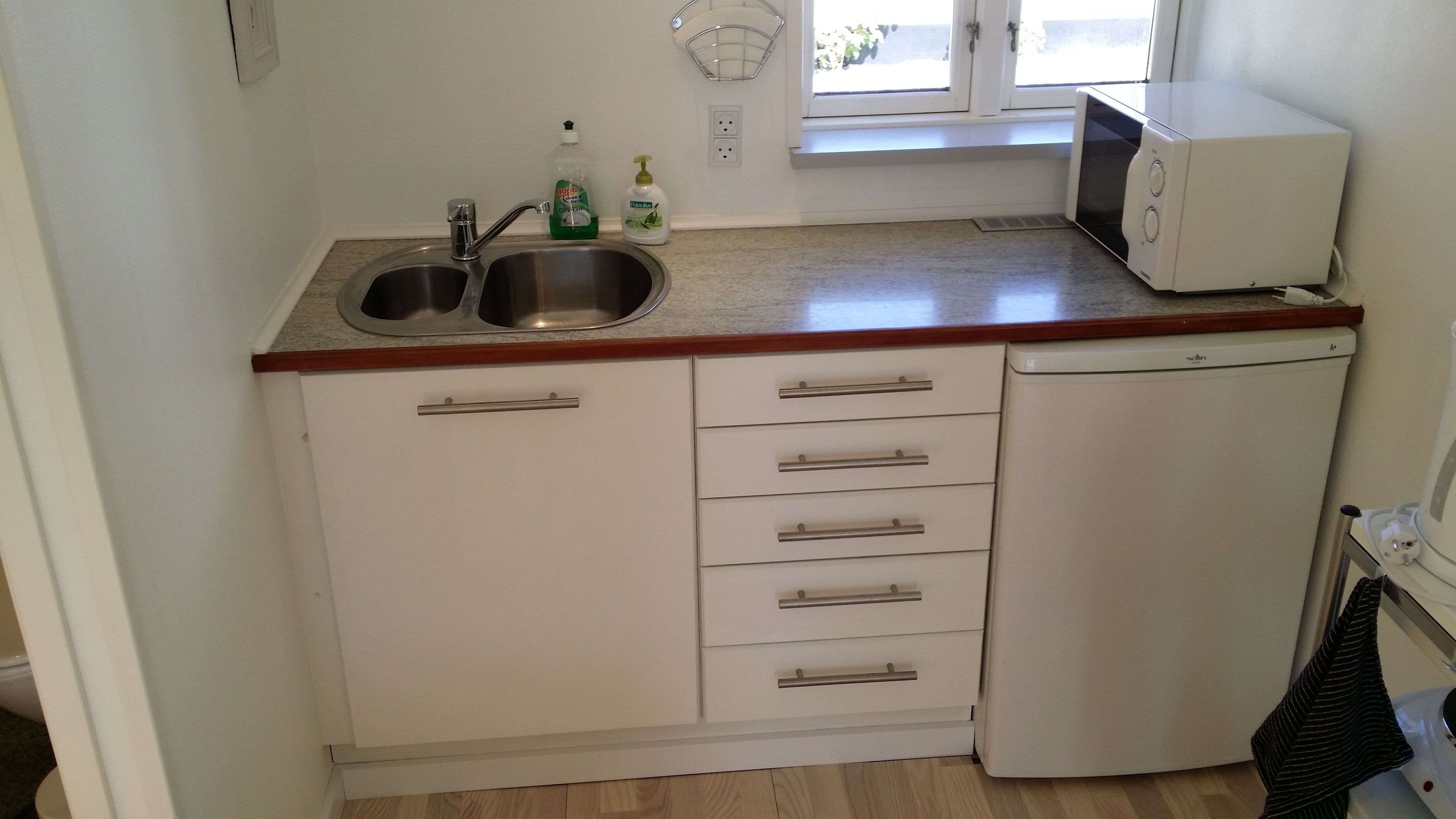 A compact kitchen with a sink, a microwave, and a refrigerator.