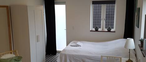 Habitación de hotel con una cama, un escritorio, una silla, una ventana y una puerta.