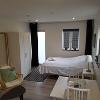 Ett hotellrum med en säng, ett skrivbord, en stol, ett fönster och en dörr.