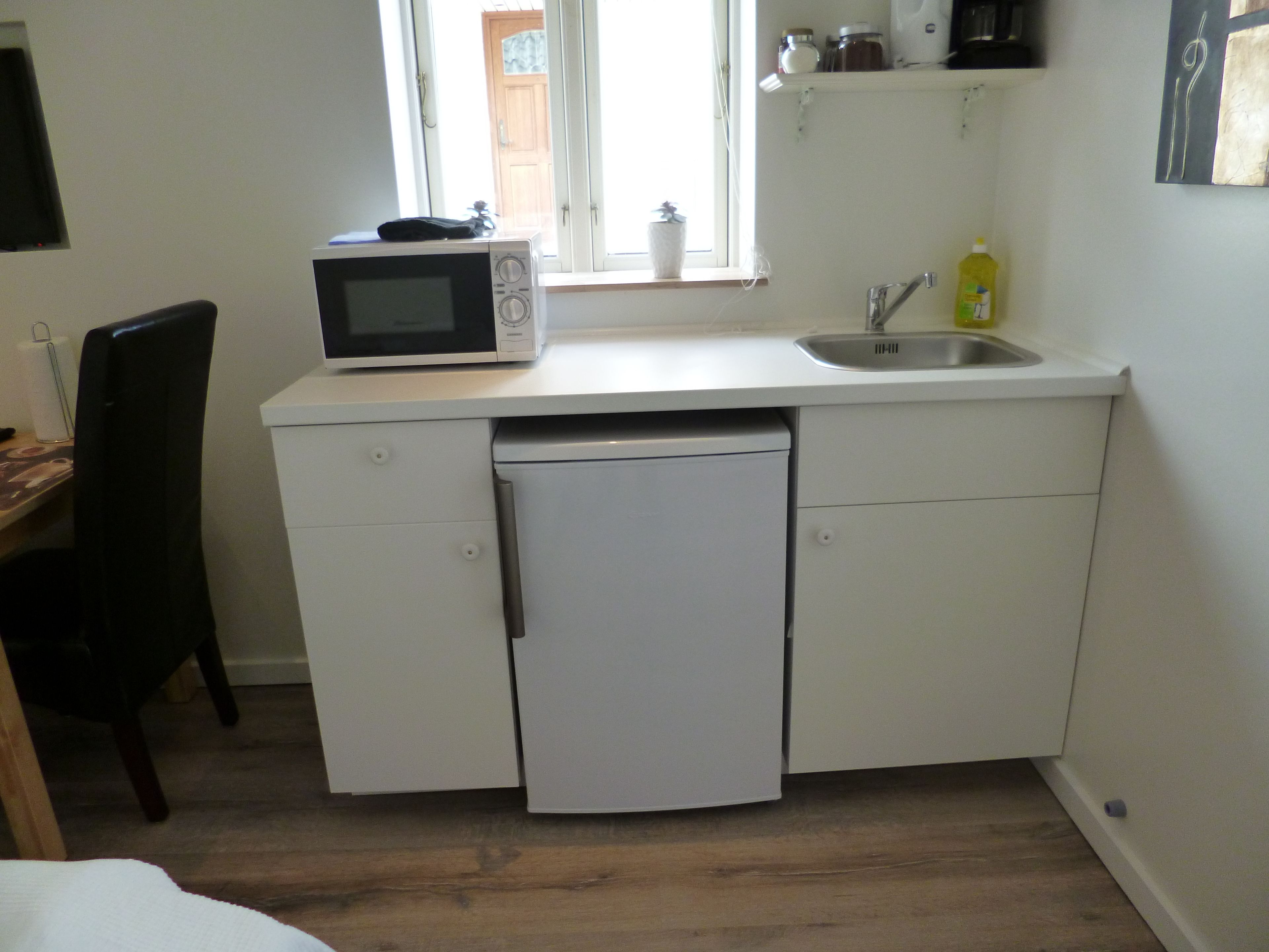 A compact kitchen with a microwave, sink, and dishwasher.