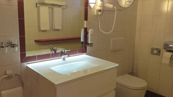 A bathroom with a white sink, a toilet, a mirror, and a towel rack.
