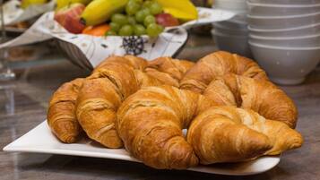 Ein Teller mit Croissants auf einer Marmorarbeitsplatte, im Hintergrund eine Obstschale.